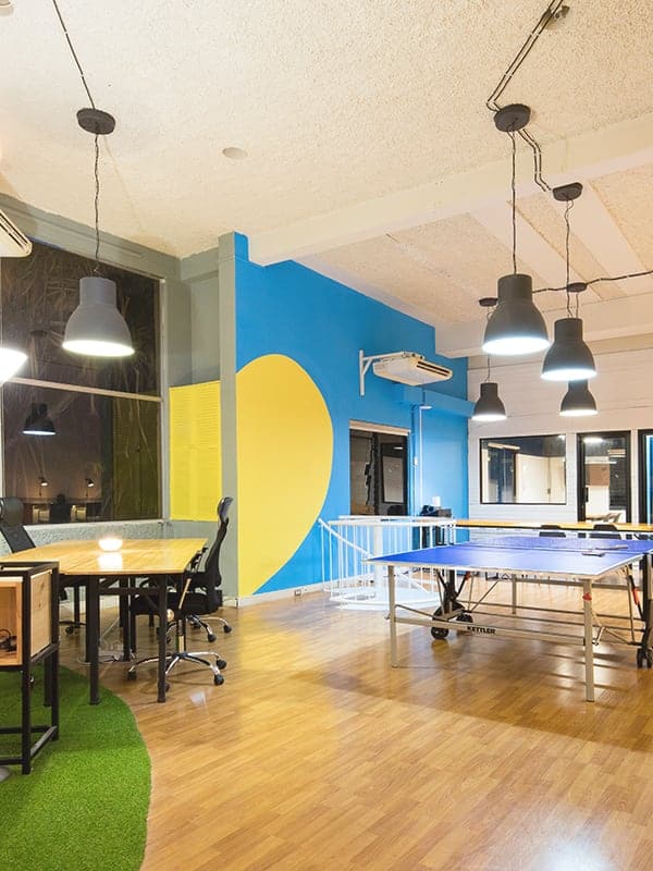 Office space featuring ping pong table, modern furnishings, and vibrant blue and yellow wall decor.